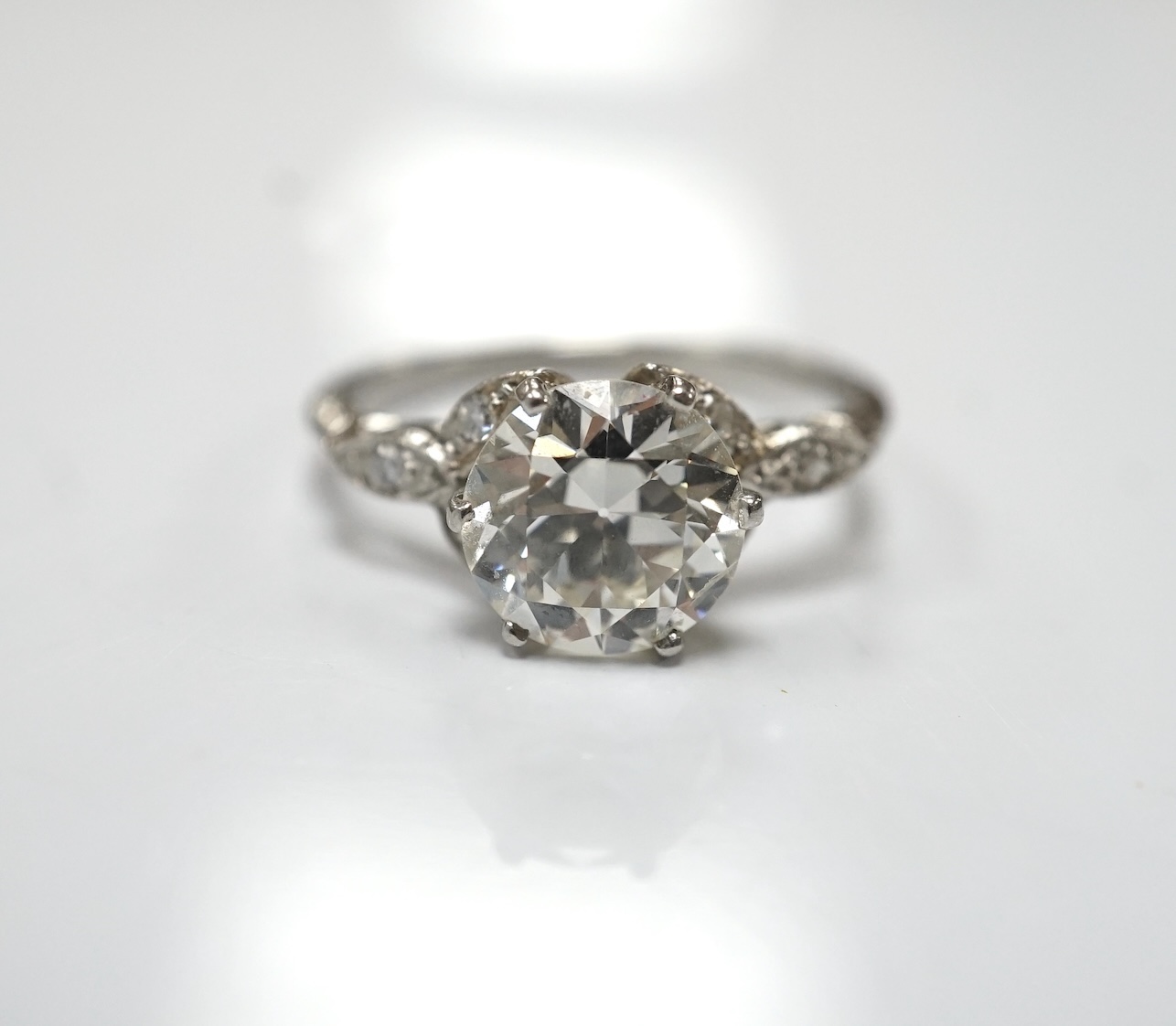 A platinum and single stone diamond set ring, with six stone diamond chip set foliate shoulders, the centre stone weighing 1.60ct, size H/I, gross weight 3.1 grams. Condition - fair